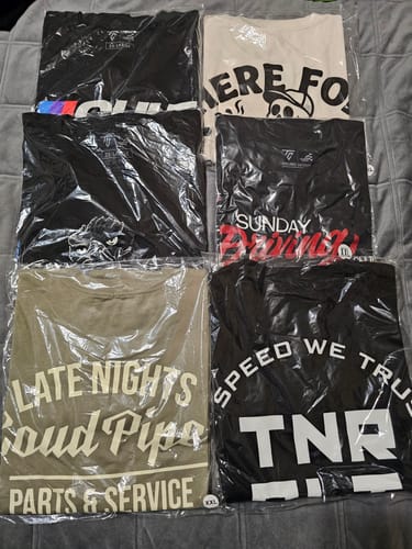 Customer's collection of six graphic T-shirts from the MYSTERY CASH BOX, folded and in plastic packaging.