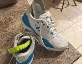 Recensore che inserisce la soletta gialla Herox Soletta Impact in una scarpa sportiva bianca.