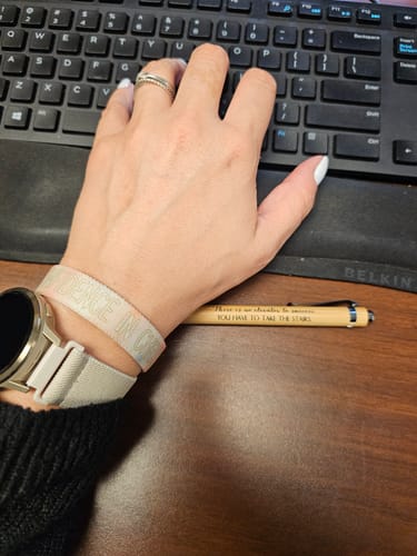 Customer wearing the light-colored 'Confidence In Christ' bracelet from the Mustard Seed Bible Pack at a desk.