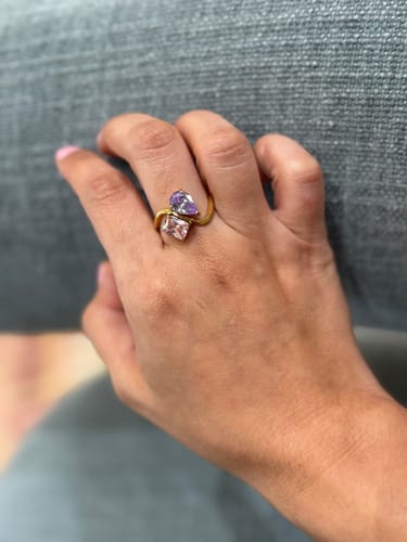 Reviewer wearing the Navae Birthstone Ring, showing the gold band with a purple pear-cut stone and a pink radiant-cut stone.