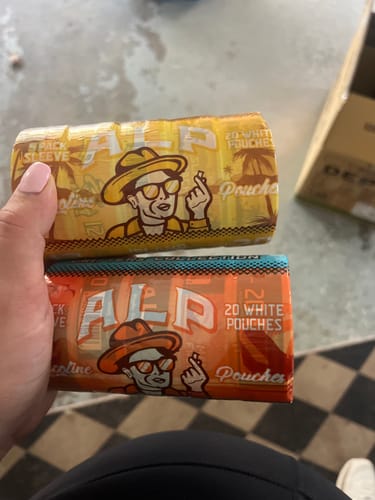 Customer holding a yellow and an orange sleeve of ALP Drifters Nicotine Pouches.