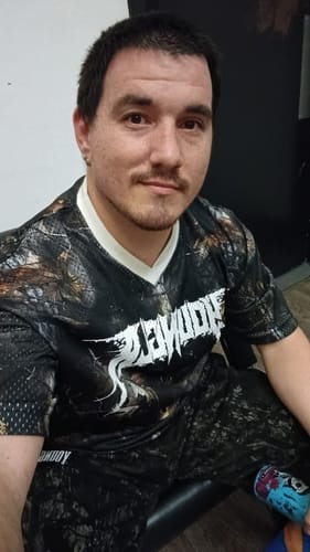 Customer seated wearing the dark, patterned Venom Jersey and matching pants, showing the front logo.