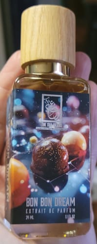 Customer holds the Bon Bon Dream perfume bottle, showing its wood cap and colorful label featuring bonbons.