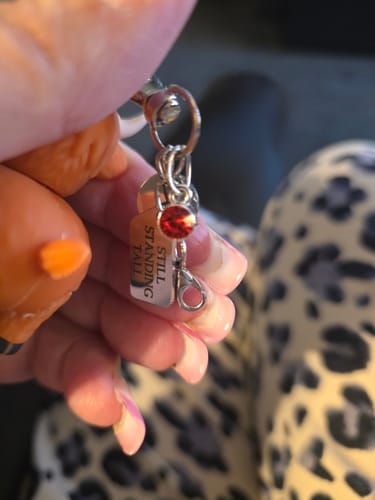 Customer holding the Highland Cow keychain, showing the red gemstone and engraved metal tag.