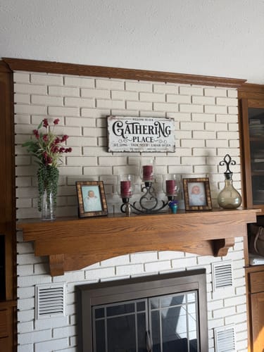 Customer's Gathering Place sign hung on a white brick wall above a decorated fireplace mantle.