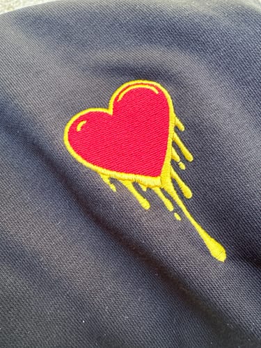 Gros plan d'un client sur le cœur brodé du sweat à capuche Hoodie Coeur.