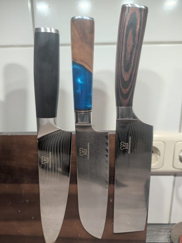 Kunde zeigt drei verschiedene Premium-Küchenmesser mit verzierten Klingen und Griffen.