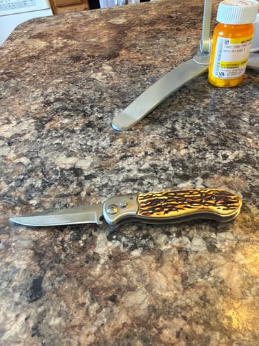 Customer's Buck Stag Switchblade Knife open on a counter, showing its textured handle.