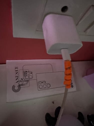 Customer's orange spiral cable protector wrapped around a white charging cable plugged into an outlet.