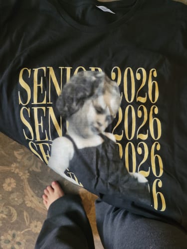 Reviewer showing their black personalized senior shirt, focusing on the custom photo print over the 'SENIOR 2026' text.