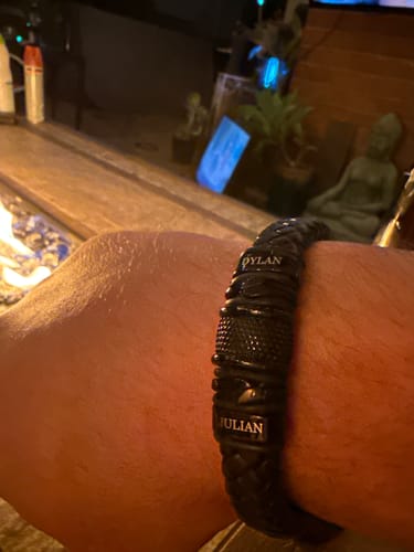 Customer wearing the personalized black bracelet with visible engravings for 'Dylan' and 'Julian'.