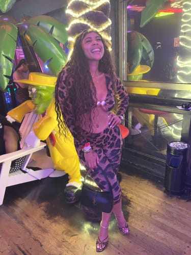 Reviewer smiling while wearing the Naked Print Cutout Capri Jumpsuit in a well-lit venue.