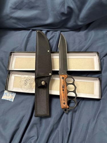 Customer's Trench Raider Pakkawood Fixed Blade with its black sheath and open boxes on a blue surface.
