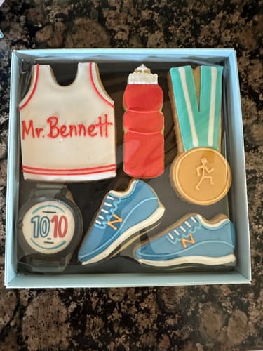 Customer's personalized Running Biscuit Box with decorated biscuits showing a vest with 'Mr. Bennett' written on it.
