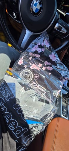 Customer showing several new STREET LEGEND TEEs in their clear packaging on a car seat.