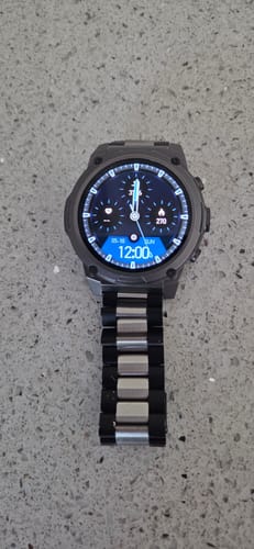 Customer's rugged smartwatch with a two-tone metal band, shown on a speckled countertop.