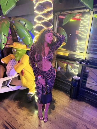 Reviewer posing in the long-sleeved Naked Print Cutout Capri Jumpsuit at a themed bar.