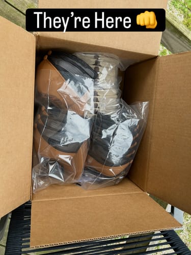 Customer's open shipping box filled with new Custom Leather Patch Trucker Hats in packaging.