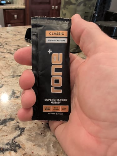 Customer holding a black, single-serving packet of Classic SuperCharged Honey.