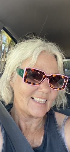 Reviewer smiling in a car while wearing the color-block Deco Sunglasses with tortoiseshell and pink frames.