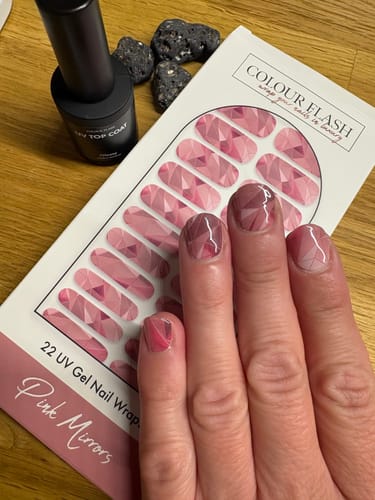 Eine Kundin zeigt ihre Nägel mit den „Pink Mirrors“ UV-Gel-Nagelfolien, die Hand liegt über der Produktverpackung.