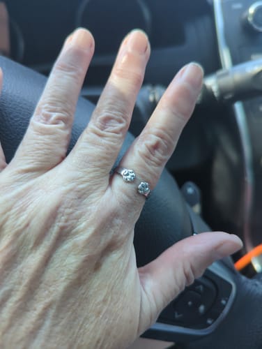 A customer's hand wearing the silver Paw Hug Ring on their finger inside a car.