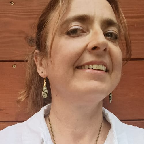 Reviewer smiling while wearing the speckled Dalmatian Jasper faceted drop earrings.