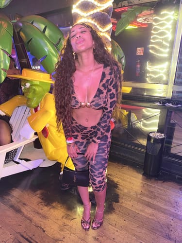 Customer posing in the animal-print Naked Print Cutout Capri Jumpsuit at a nightclub.