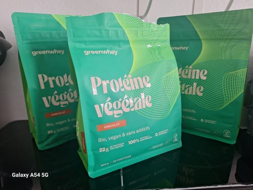Avis d'un client montrant trois sachets verts de Protéine Végétale saveur chocolat sur une surface noire.