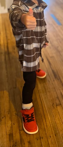 Customer's child giving a thumbs-up while wearing the red Kid's Wonderland Winter Barefoot Shoes.