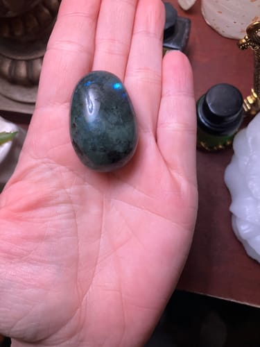 Customer holding the dark, polished labradorite crystal in their open palm.