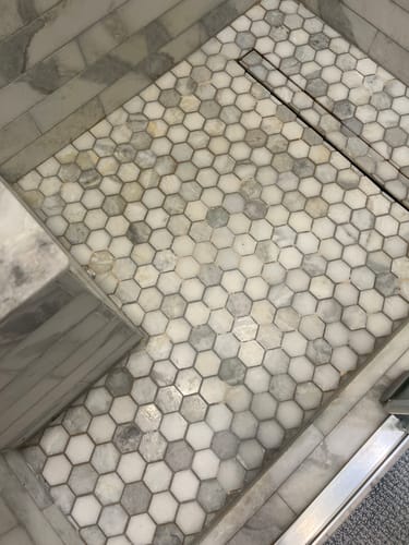 Reviewer's clean natural stone shower with hexagonal tiles after using the Shower Starter Bundle.