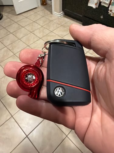 Reviewer holding the red Turbo Keychain attached to a black Volkswagen key fob.
