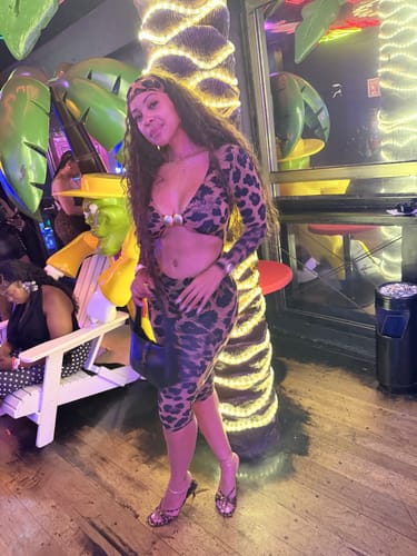 Customer in a full-body view of the Naked Print Cutout Capri Jumpsuit with a matching headband.