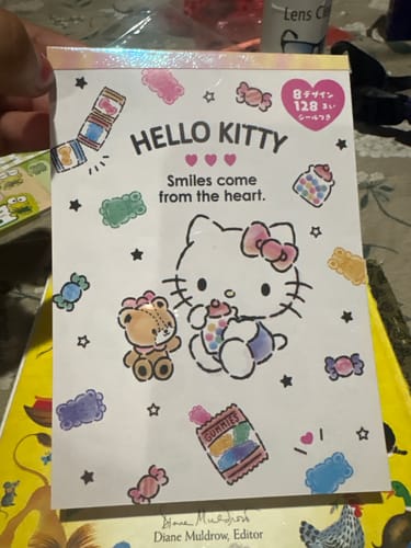 A customer holds the Sanrio Character Memo Pad, showing the front cover design featuring Hello Kitty and a bear.