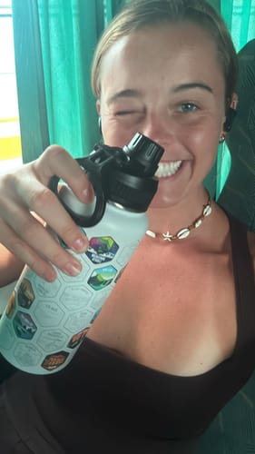 Customer smiling and holding a white water bottle with the black Chug Lid attached.