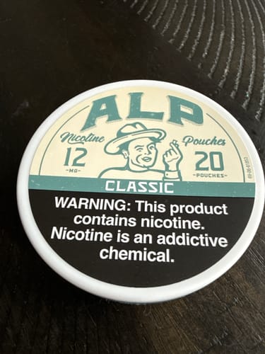 Customer's can of ALP Classic Nicotine Pouches sitting on a dark table.