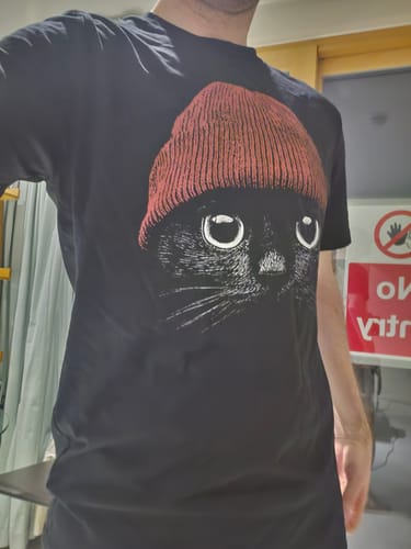 Reviewer wearing the black Statement Made t-shirt, which features a large graphic of a black cat in a red beanie.