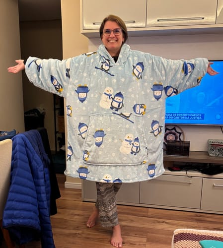 Cliente sorrindo com os braços abertos para mostrar o seu Sleepo Pinguim azul com estampa de pinguins.