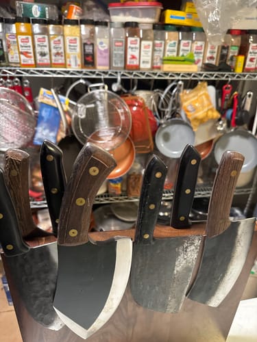Reviewer's set of several cleaver-style knives with wooden handles displayed in a knife block.
