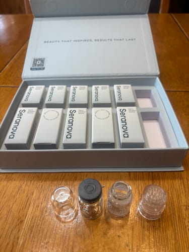 Customer's Seranova Micro Infusion System box with cartridges and four vials on a wooden table.
