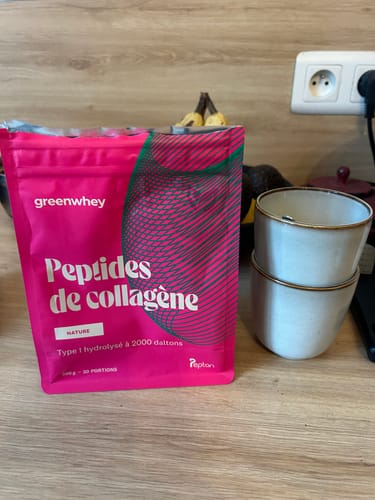 Le sachet rose de Peptides de collagène du client sur un comptoir de cuisine en bois.