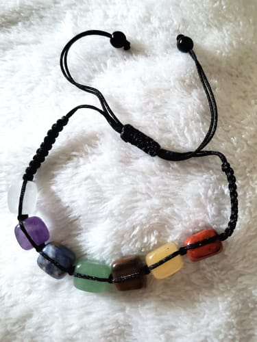 Customer's adjustable crystal bracelet with seven colorful stones on a white surface.