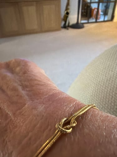 Close-up of a reviewer wearing the gold-colored Forever Knot Bracelet on their wrist.
