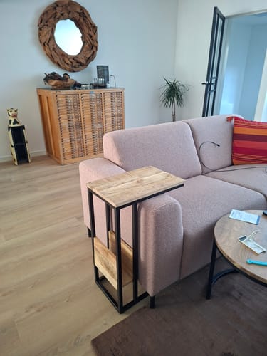 De Bijzettafel Britt van een recensent, met mangohouten blad, die over de armleuning van een bank is geschoven.