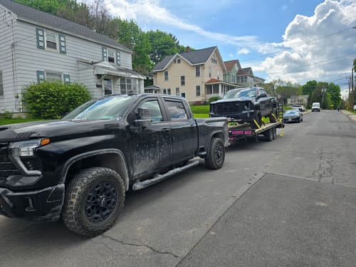 Customer's black Chevy Silverado showing the wider stance from the installed 2" wheel spacers while towing another truck.