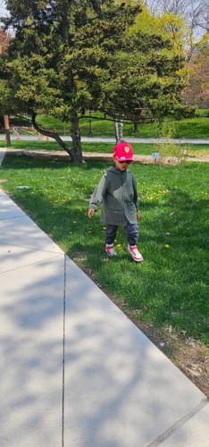 Reviewer's child wearing the red and white Kid's Wonderland Ⅰ Lite high-top shoes while standing on a grassy lawn.