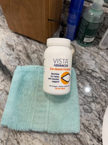 Customer's bottle of VISTA Advanced Carotenoid Formula resting on a small towel on a marble bathroom counter.