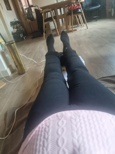 En anmelder ligger på gulvet og bruger sin Premium Chi Maskine, set fra et personligt perspektiv.