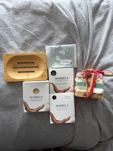 Customer's collection of Marbela Cosmetics soaps, shown in boxes and unwrapped, with a wooden soap dish.